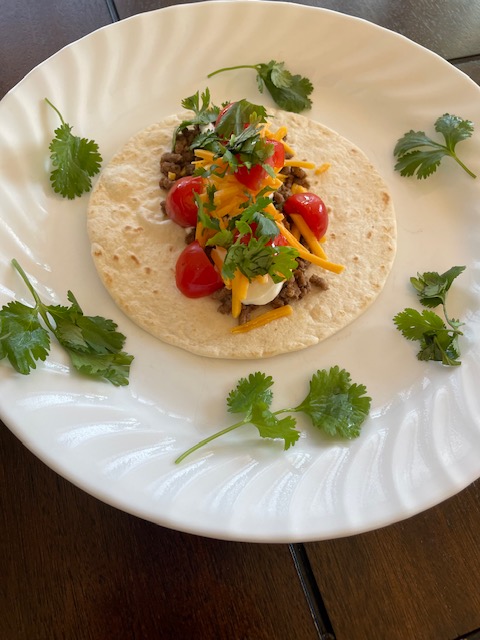 ground beef taco with tomato, cilantro, and cheese