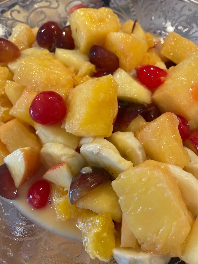 fruit salad with pineapples, apples, grapes, bananas, and cherries